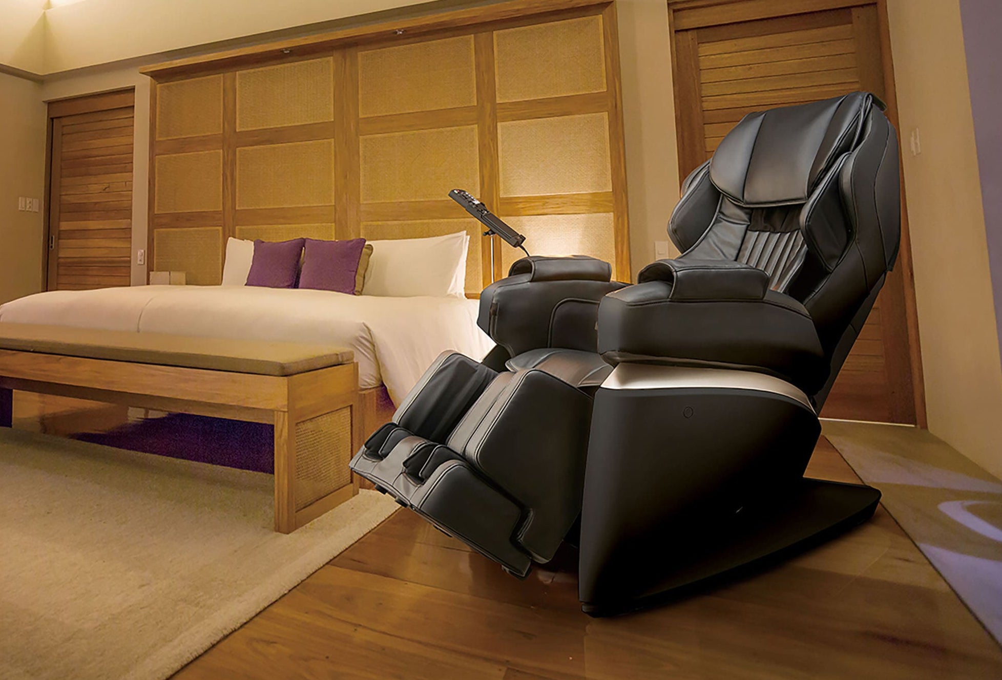 Synca Kurodo Massage Chair in a bedroom setting with wooden features and a bed in the background